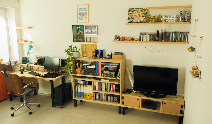 Home workspace with wooden desk, bookcase, sideboard and wall shelves, styled with books, plants and decor in a bright, minimal room.