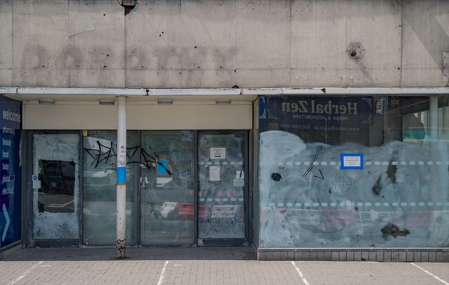 Closed and empty shop front with boarded windows, graffiti and signs removed, showing the impact of rising high street costs on small businesses.