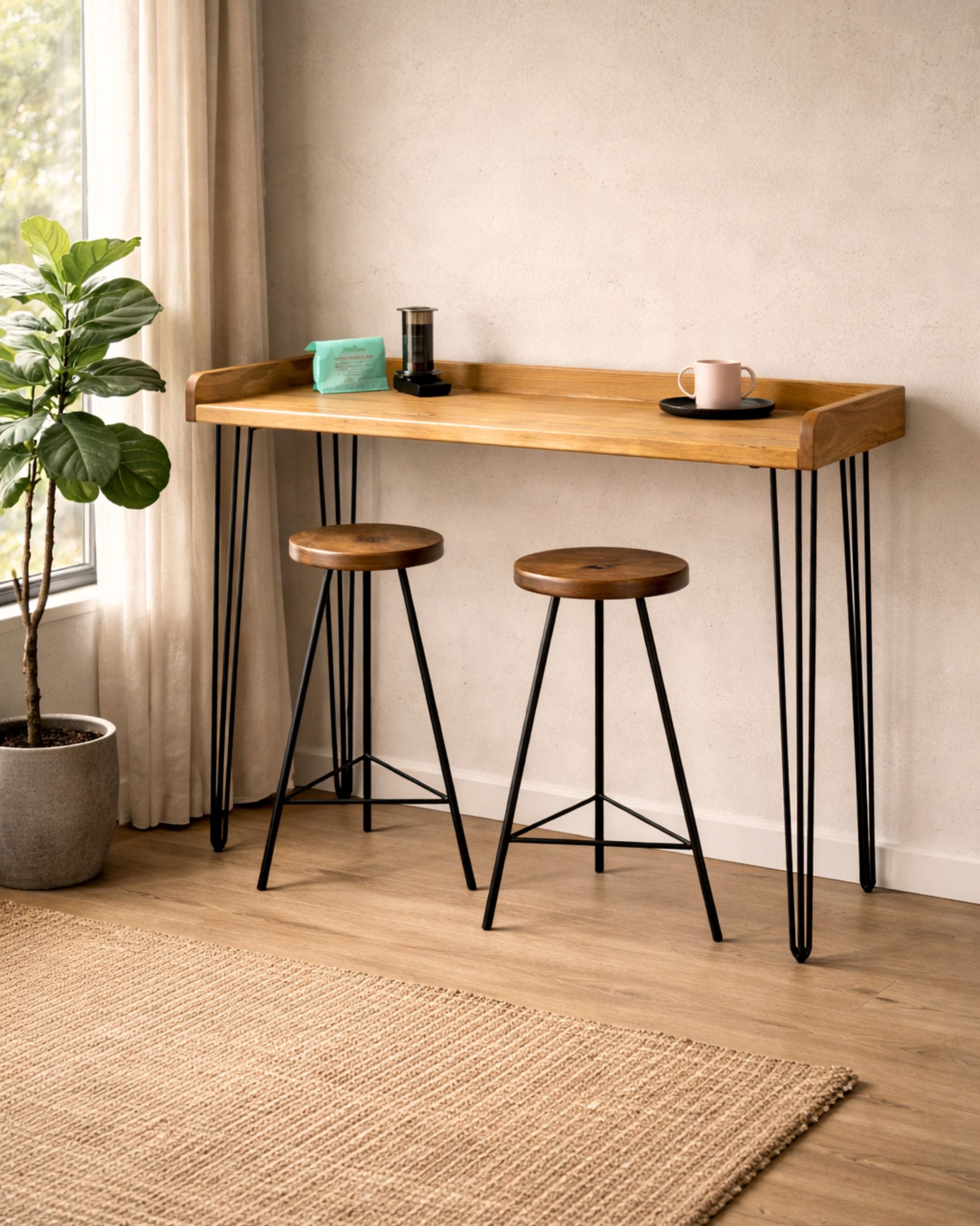 Solid wood breakfast bar with raised back edge and black hairpin legs, paired with two wooden stools in a small kitchen corner.