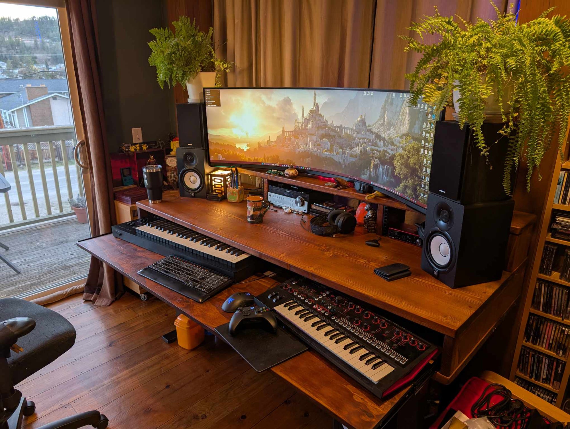 Studio Desk setup with a large monitor, keyboard, and speakers on a wooden desk.
