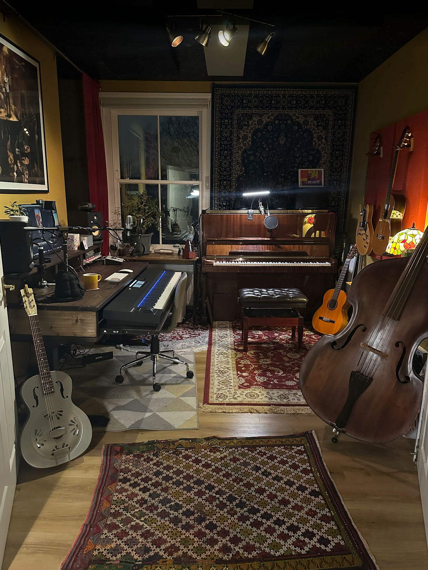 Studio desk in Music room with a piano, guitars, and other musical instruments.