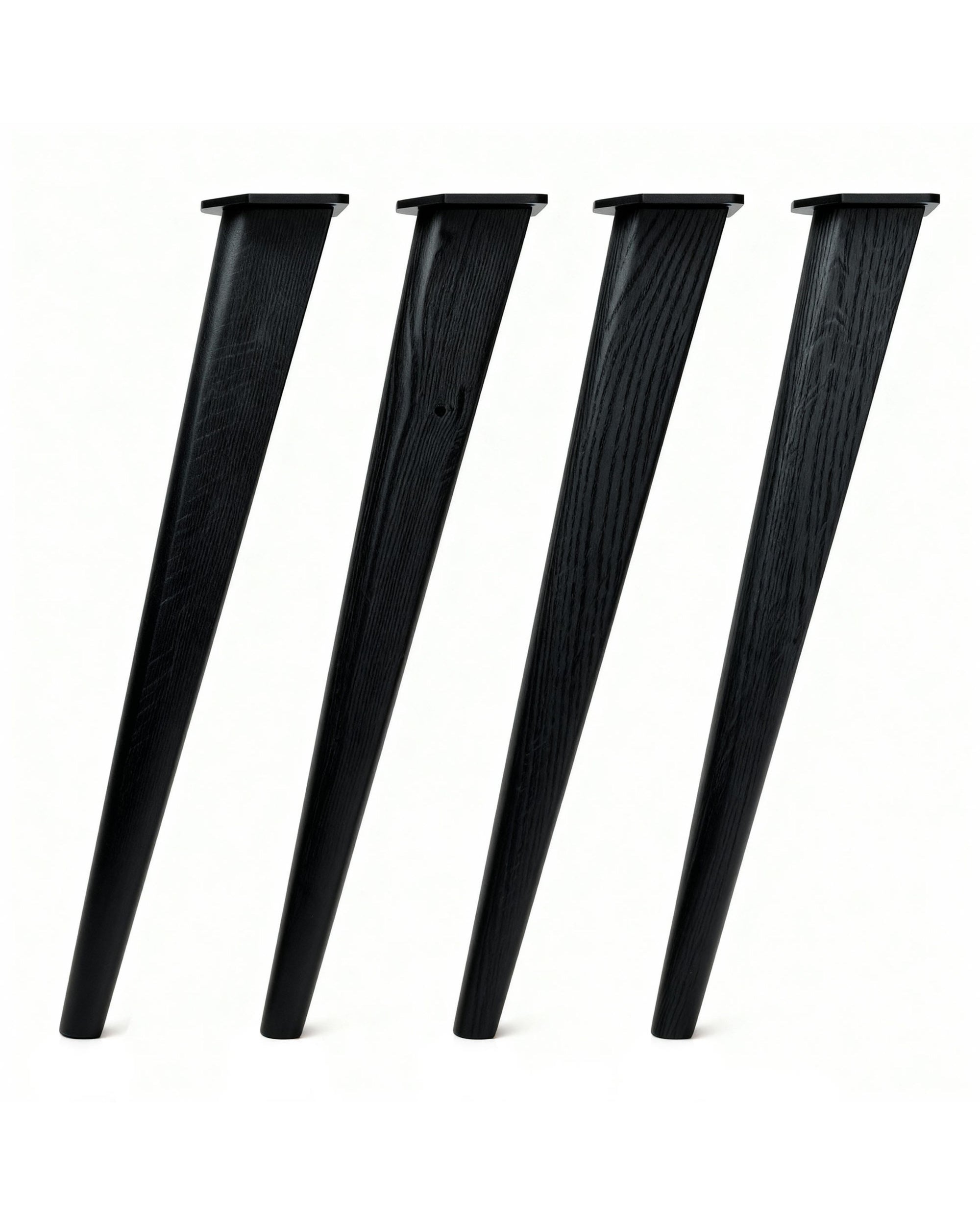 Set of four solid oak desk legs in a Scandi style, with a black finish and visible grain variation, each angled and fitted with black mounting plates.