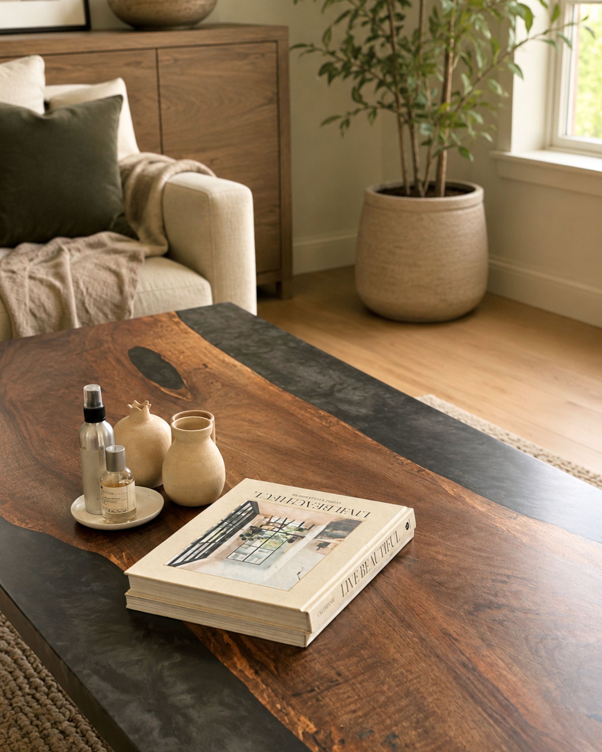 Large walnut statement coffee table with smoked black resin and matte black steel legs in a warm contemporary living room interior.